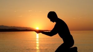 diverse man holding with the sun setting in his hand 
