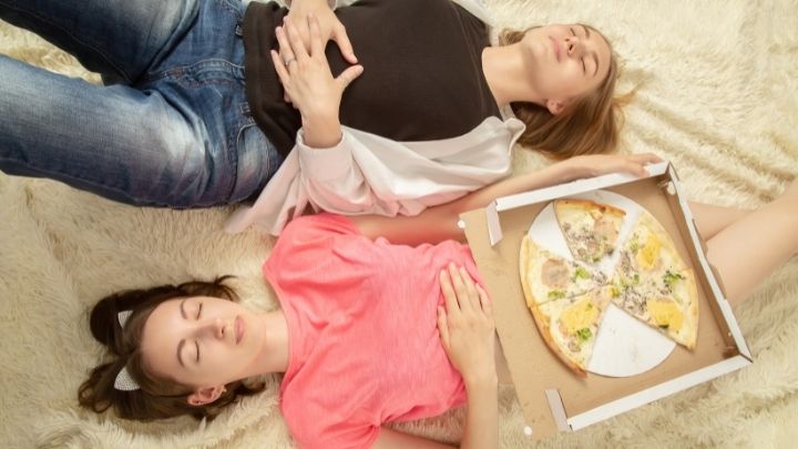 two girls that overate on pizza