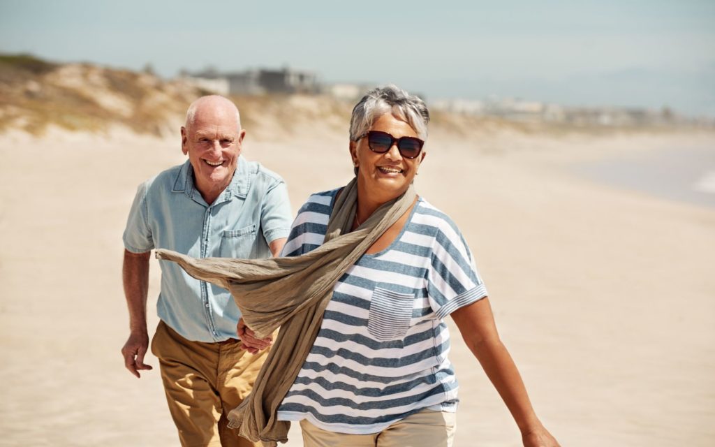 old couple running on the beach and holding hands